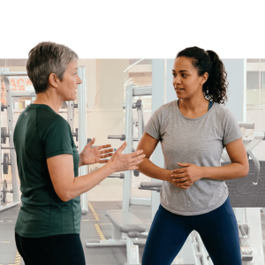 Two women engaged in conversation during a workplace wellness activity with purple background
