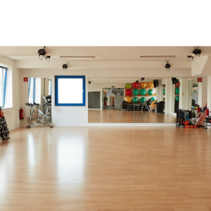 Spacious fitness studio with wooden floors, wall mirrors, training equipment, and colorful exercise balls ready for group fitness classes