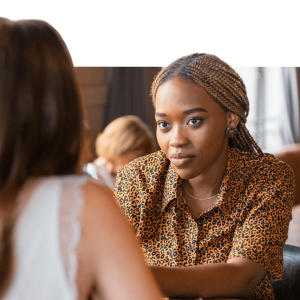 Two women in conversation during a workplace wellness session, one wearing a leopard print shirt engaging attentively with the other