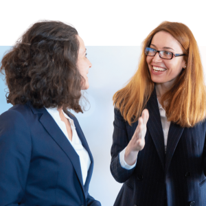 Two professional women in business suits having a friendly conversation and smiling
