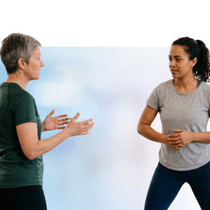 Two women engaged in conversation with animated hand gestures and smiling expressions against a blue sky background