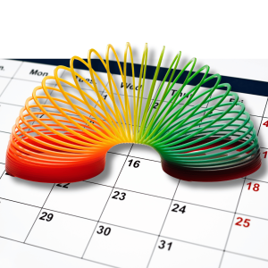 Colorful coiled spring toy showing gradient from red to green positioned on a calendar, symbolizing scheduling and time management for wellness programs
