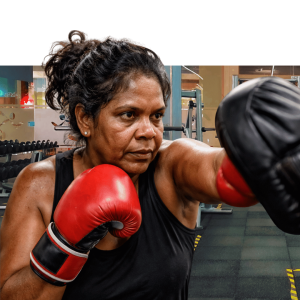 Female boxing instructor teaching young male student proper punching technique with red and blue boxing gloves