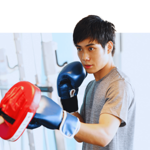 Woman smiling while wearing red boxing gloves in a boxing stance against a green and yellow background