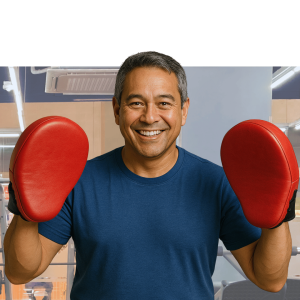 Smiling man in blue shirt wearing red boxing gloves against green and yellow gradient background